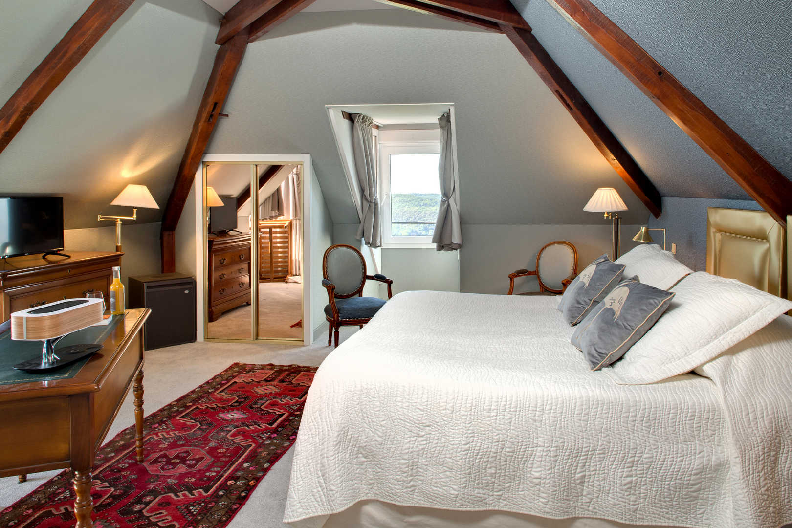 Vue intérieure d'une grande chambre avec poutres en bois apparentes dans l'hôtel de charme en Dordogne, l'Esplanade