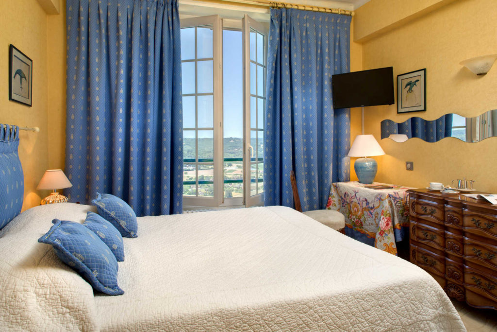 Vue sur une chambre avec des murs jaunes et des rideaux bleus dans l'hôtel L'Esplanade